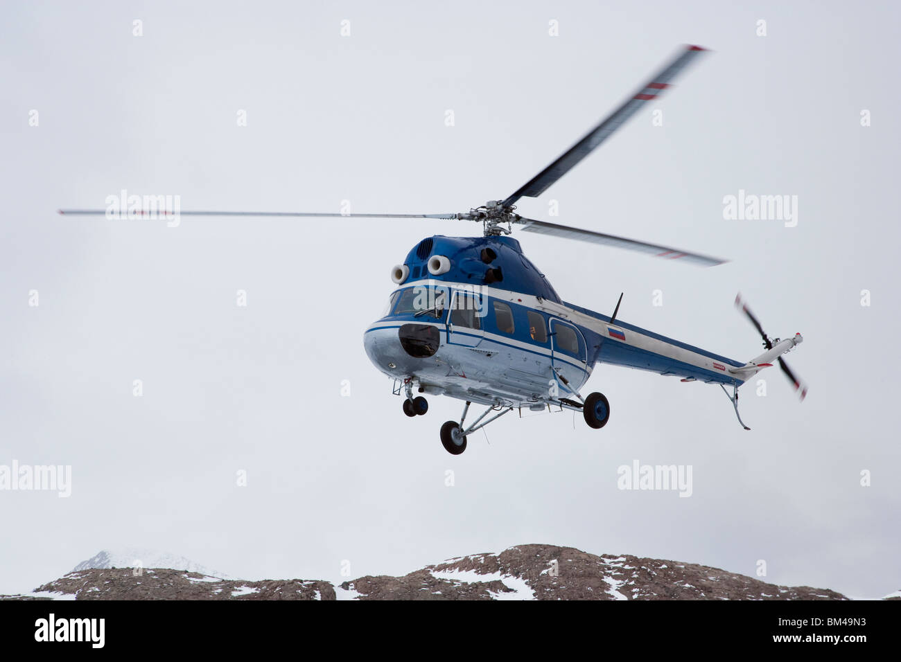 Close up de l'hélicoptère en vol au dessus de rocky mountain top en Antarctique fond de ciel couvert enlevé identification glacier lointain Banque D'Images