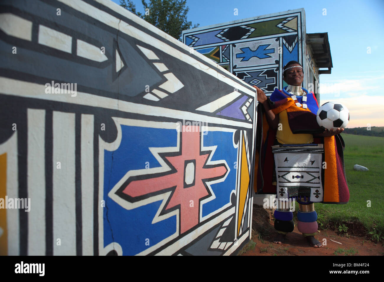 Une femme avec des couleurs traditionnelles Ndebele tribe stand avec un ballon de soccer dans un village culturel à Mpumalanga, Afrique du Sud Banque D'Images