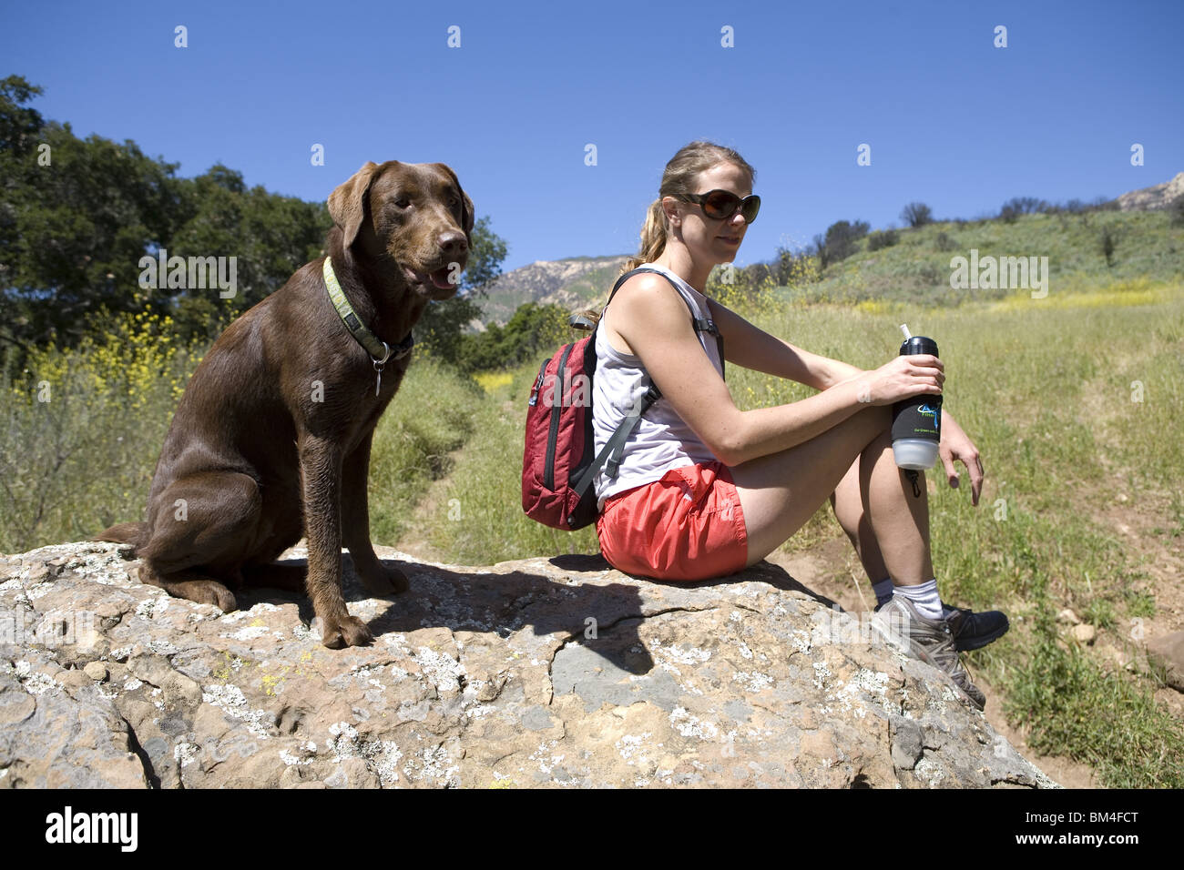 Un coureur prend une pause sur la piste avec son chien pour un verre d'eau. Banque D'Images