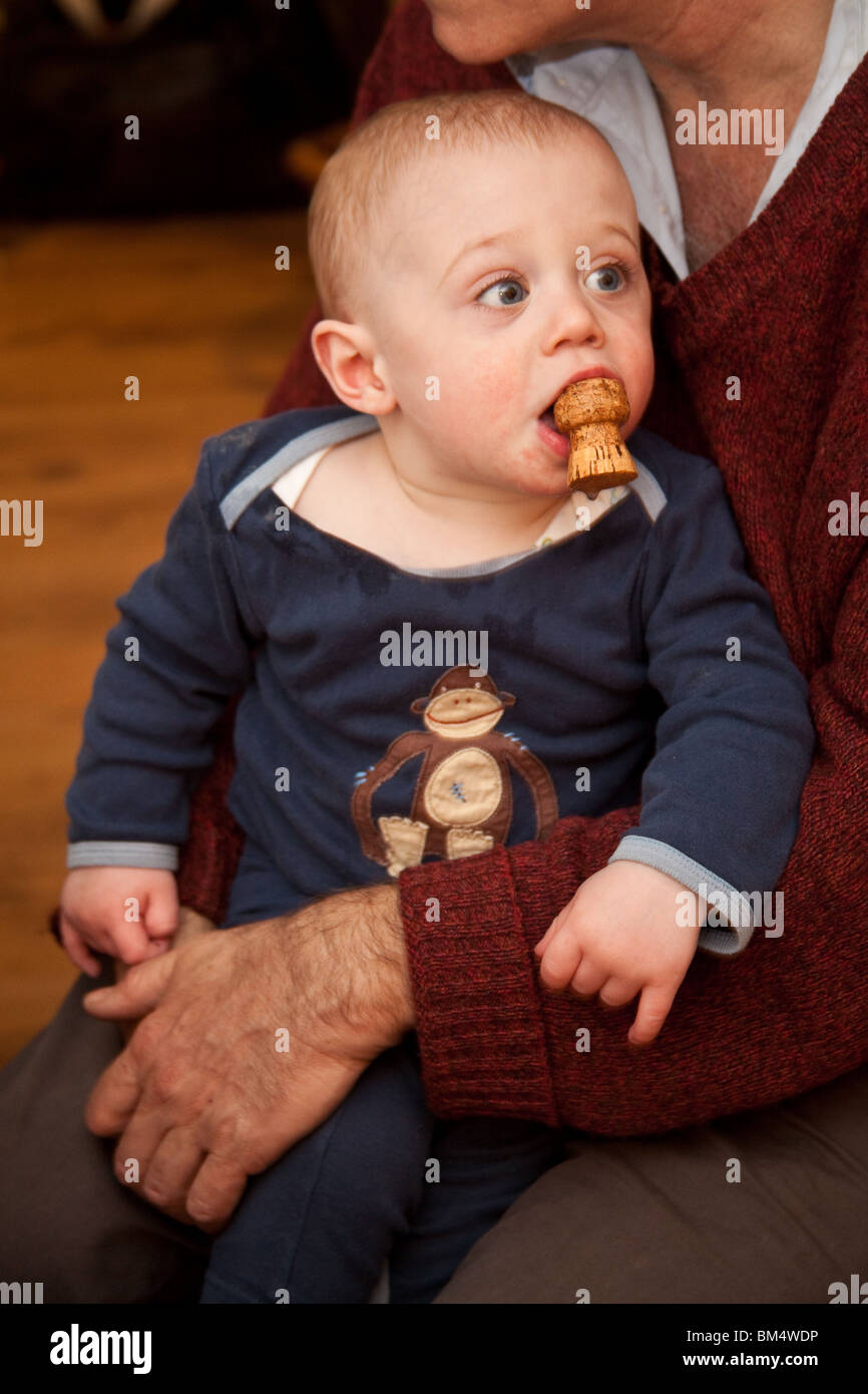 Bébé garçon 11 mois, d'un bouchon de champagne dans sa bouche. Banque D'Images