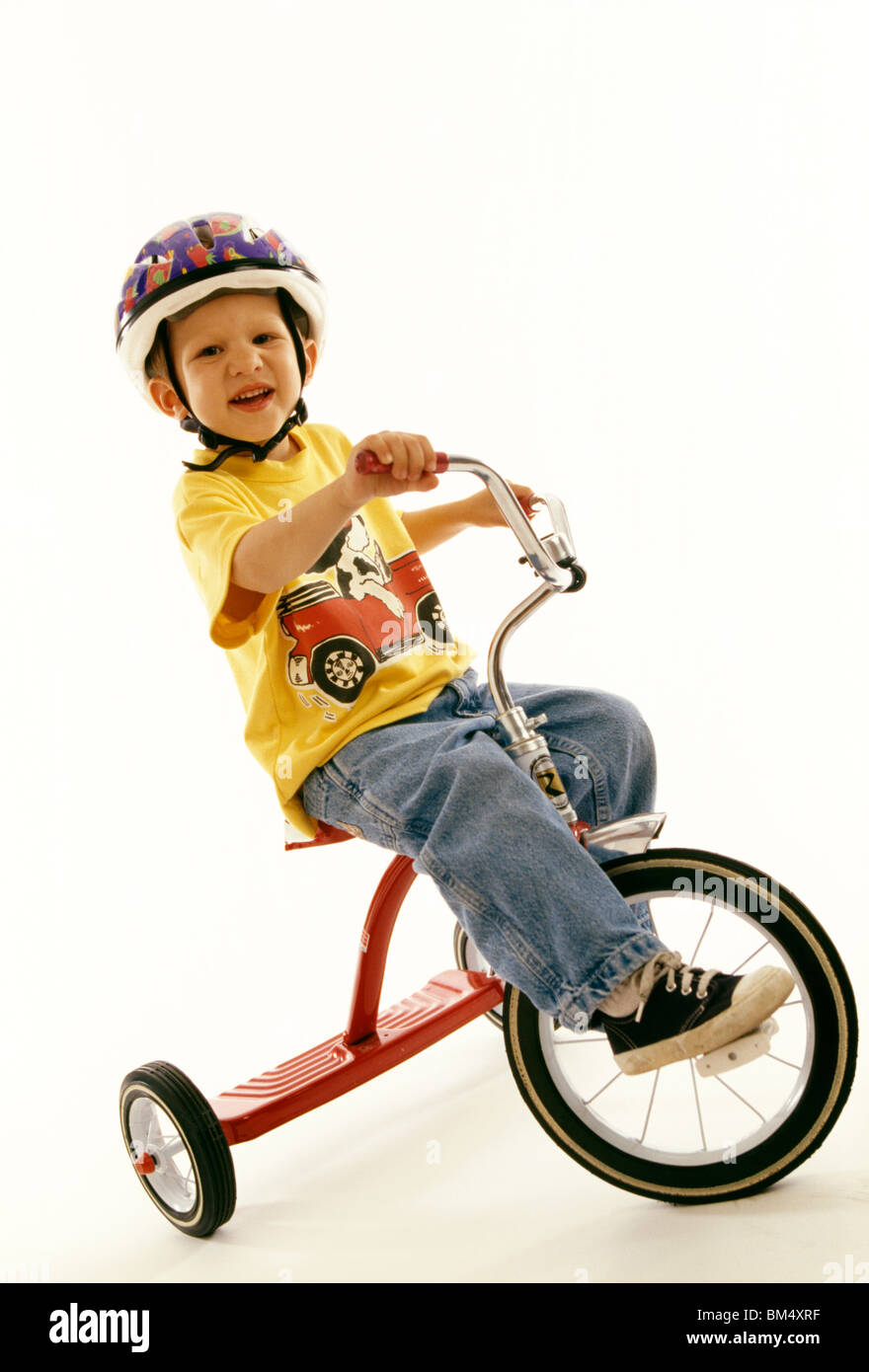 Portrait de quatre ans garçon sur son tricycle. Banque D'Images