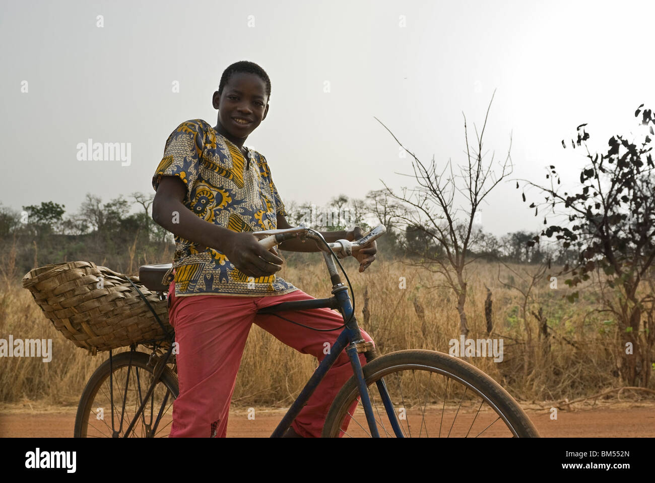 Bassari boy riding sa bicyclette, Village d'Ibel, Pays Bassari, Sénégal, Afrique. Banque D'Images