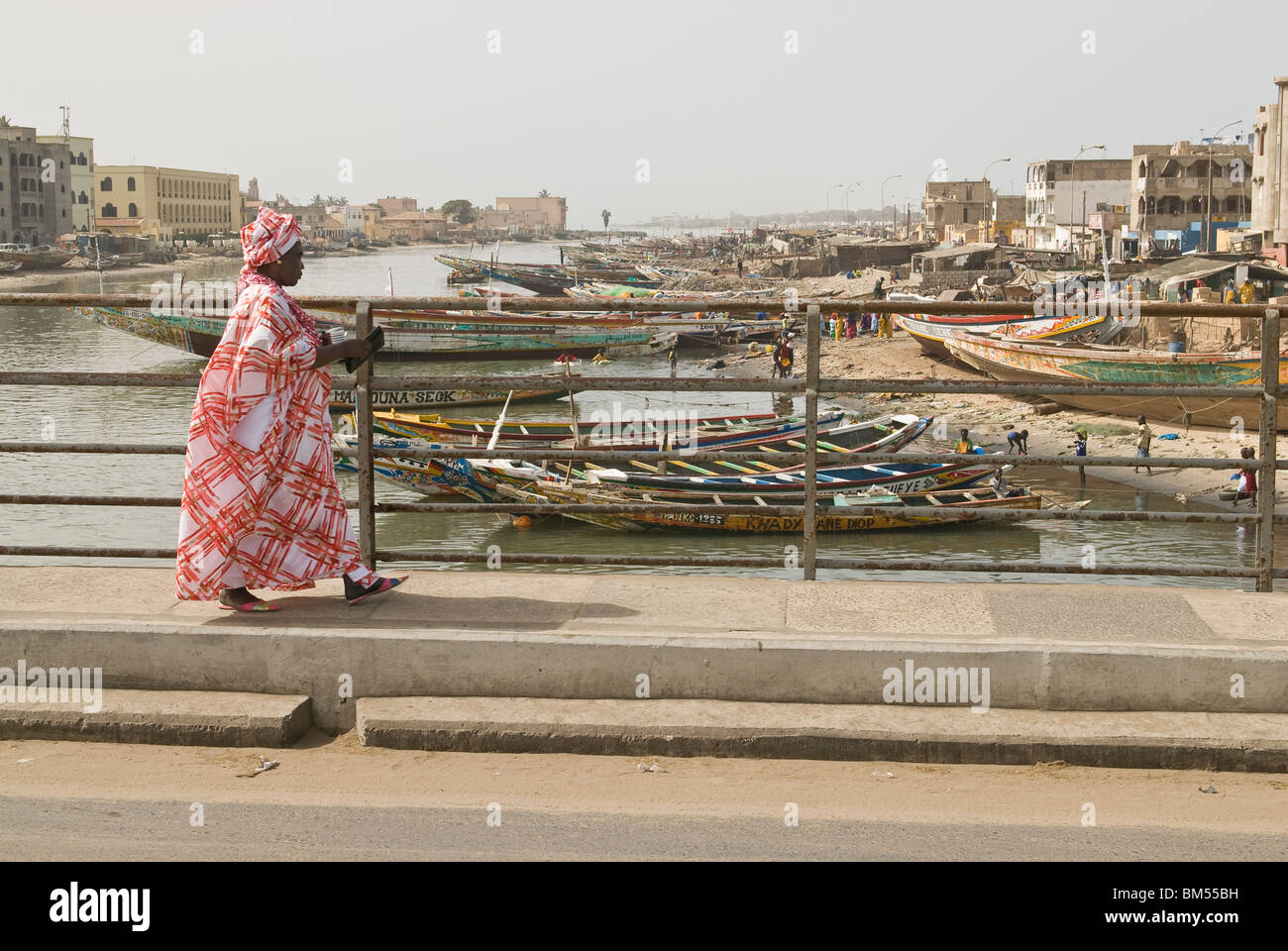 Vieille Femme avec des vêtements traditionnels de traverser un pont, Saint-Louis, Sénégal, Afrique. Banque D'Images