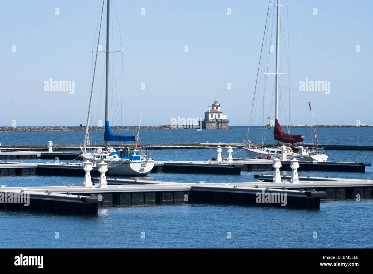 Voiliers amarrés dans le yacht club sur le lac Ontario, Oswego NY avec un phare dans l'arrière-plan Banque D'Images