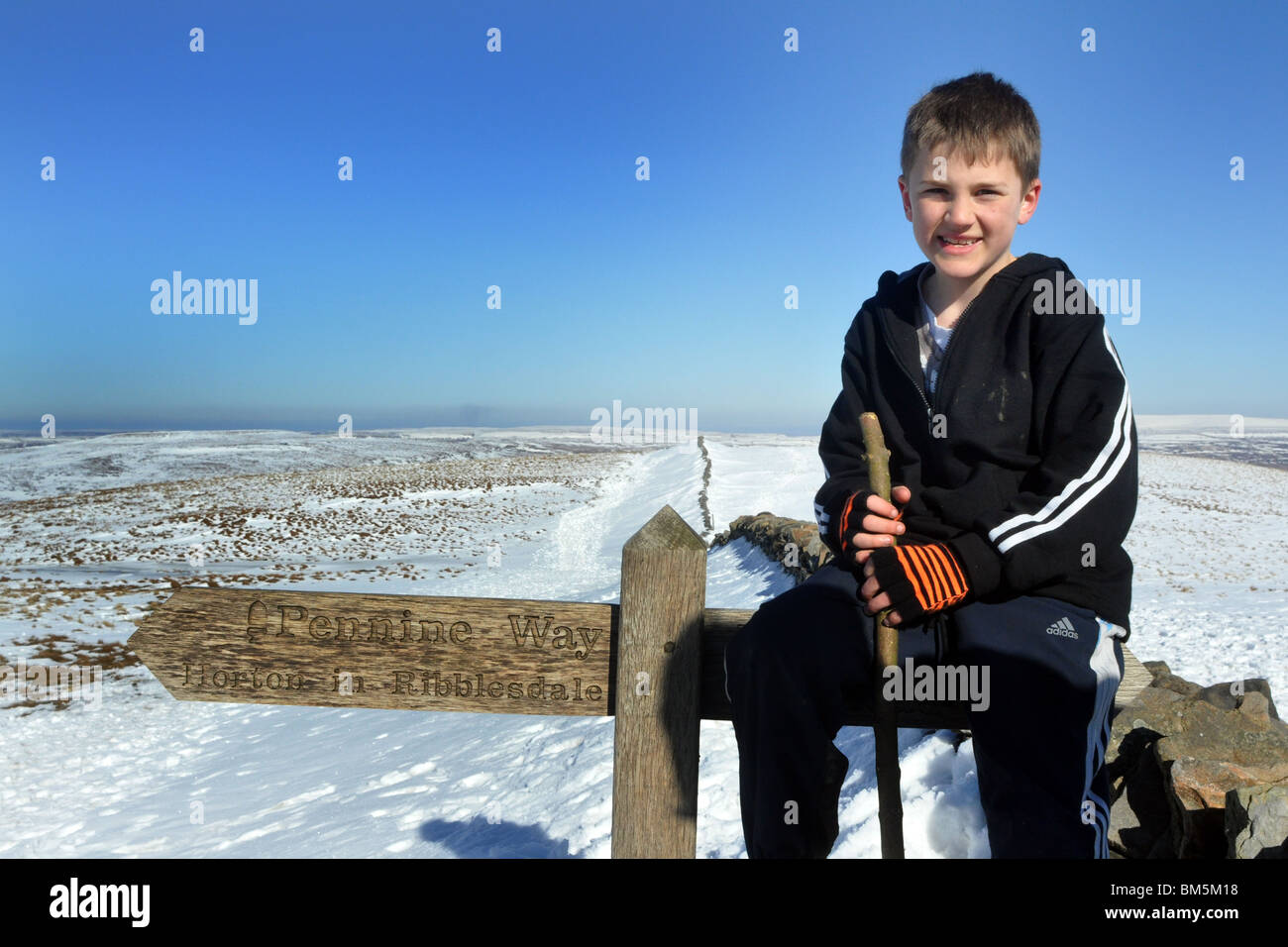 Un garçon de 9 ans atteint le sommet d'un pic enneigé dans le Yorkshire Dales Banque D'Images