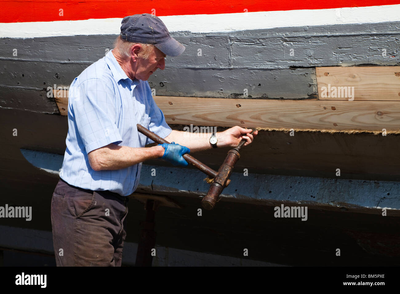 Navire Master Builder, John Gaff, la réparation de la coque d'un bateau de pêche en utilisant la méthode traditionnelle de l'étoupe d'emballage au sujet des lacunes Banque D'Images