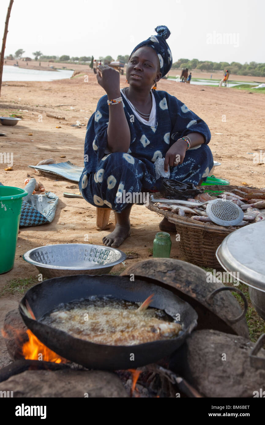 Une femme vend du poisson frit pour voyageurs au passage de bac à Djenné, au Mali. Banque D'Images