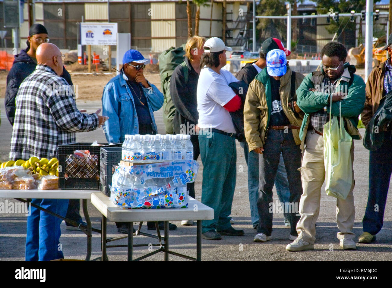 Un ministre local (chemise à carreaux) prêche pour un groupe d'hommes sans abri en ligne de nourriture sur un terrain vague dans la région de North Las Vegas, Nevada. Banque D'Images