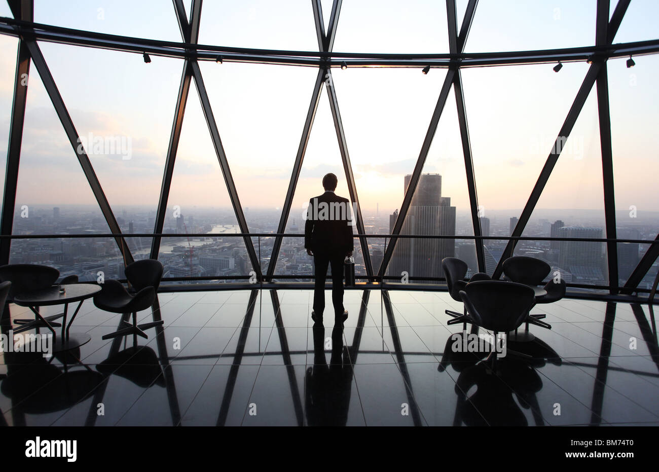 Un homme d'affaires stand avec son porte-documents en haut de le Gherkin gratte-ciel dans la ville de Londres, au Royaume-Uni. Banque D'Images