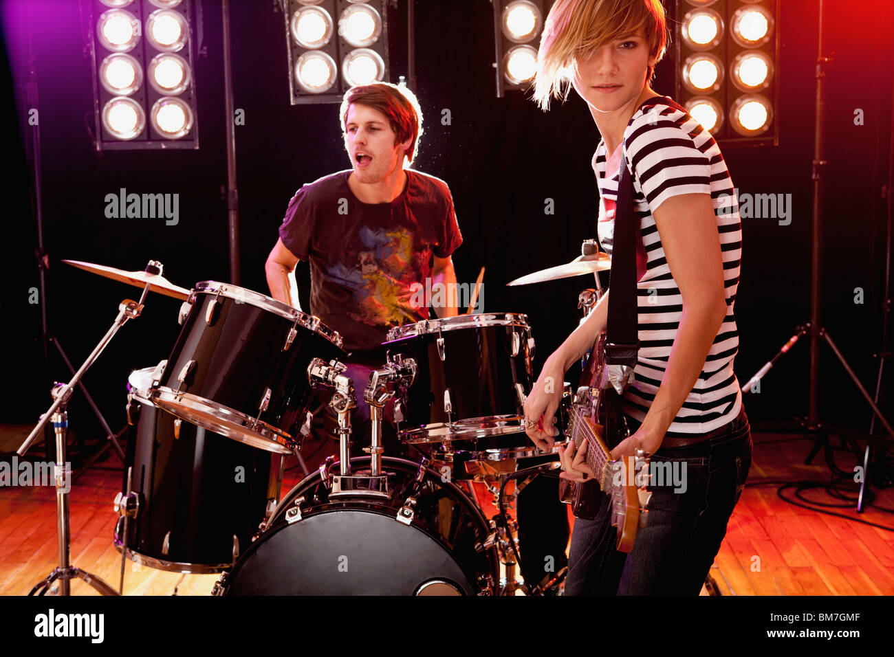 Un homme à jouer de la batterie et d'une femme qui joue de la guitare sur scène dans un groupe de rock Banque D'Images