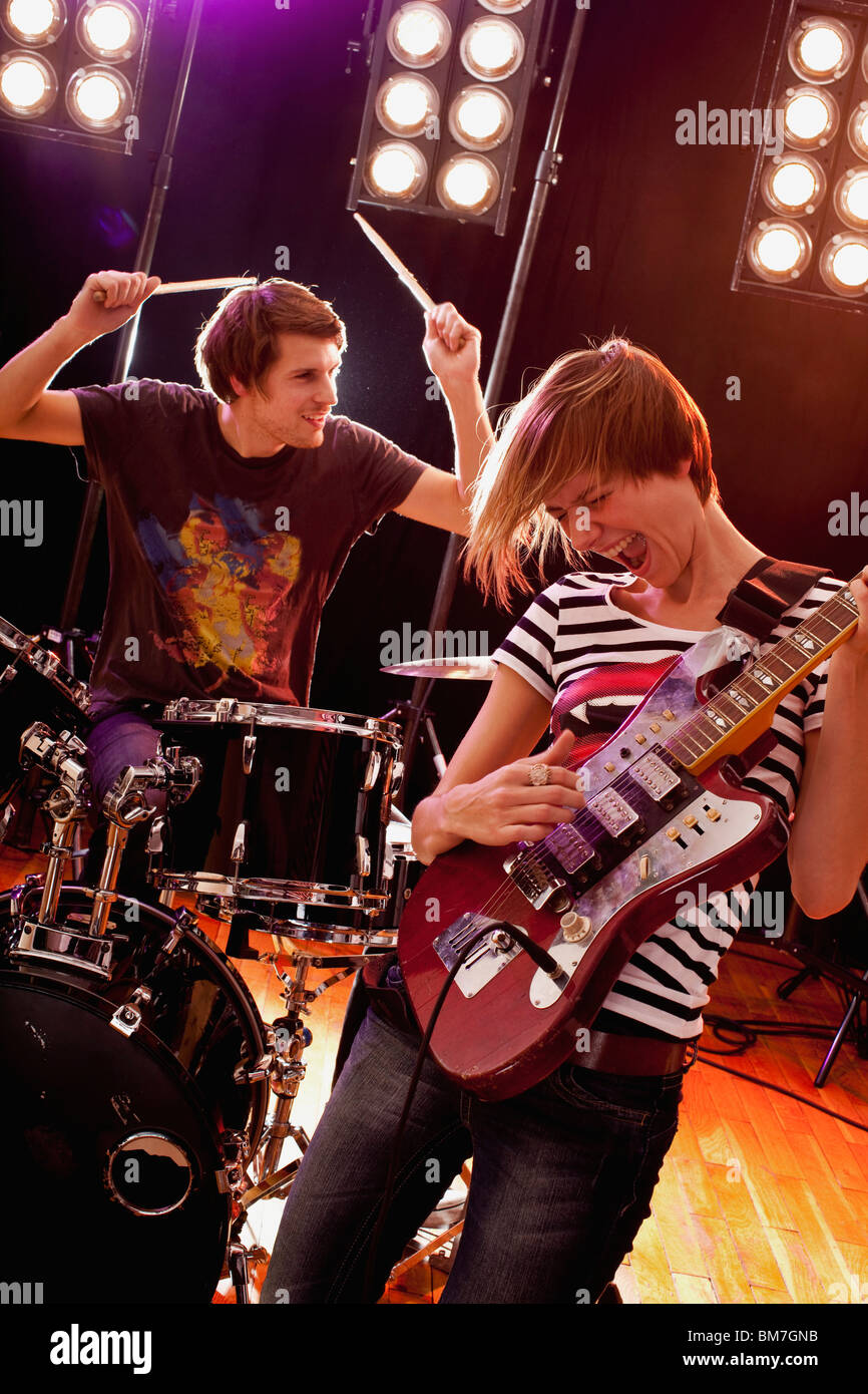 Un homme à jouer de la batterie et d'une femme qui joue de la guitare dans un groupe de rock sur scène Banque D'Images