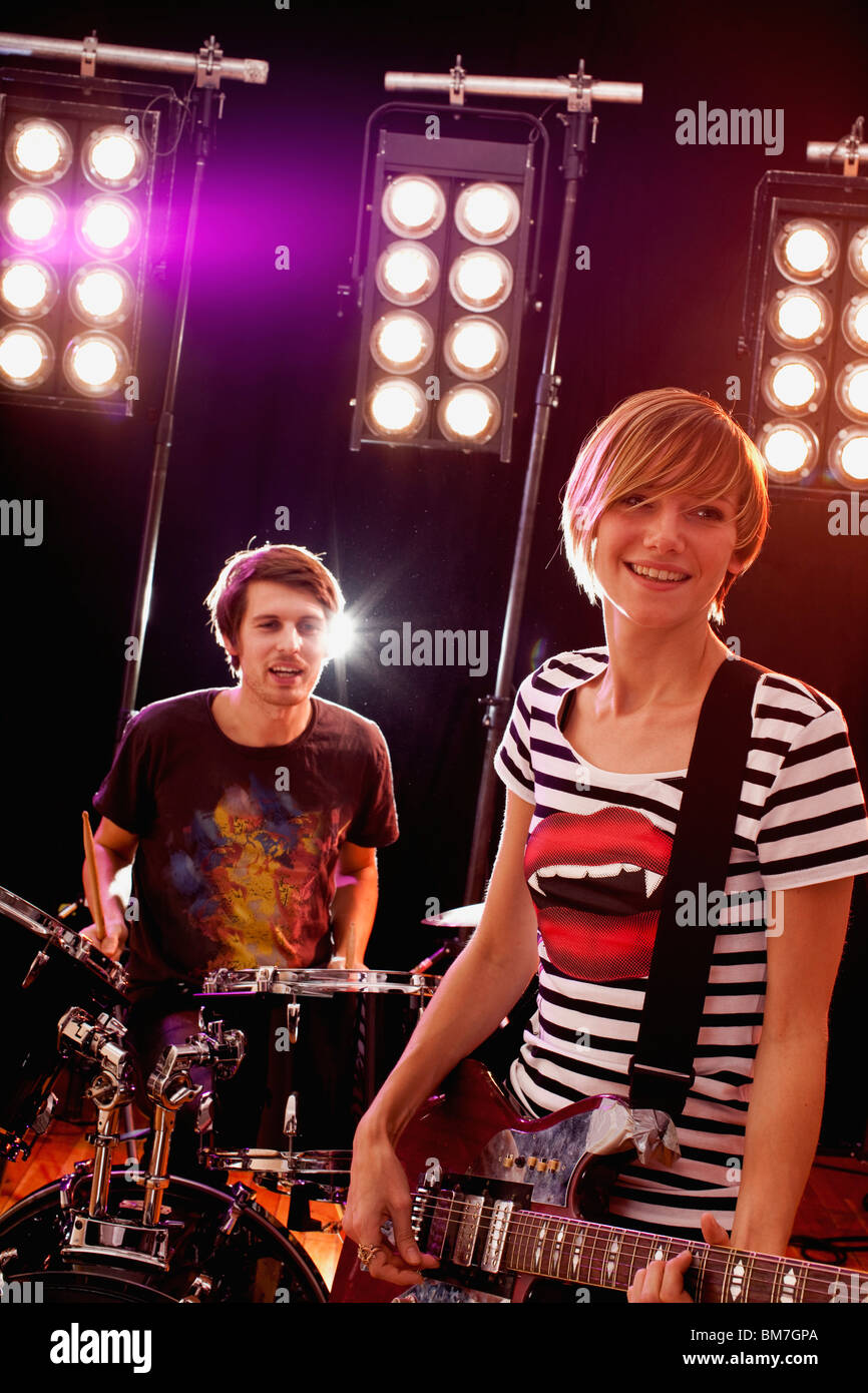 Un homme à jouer de la batterie et d'une femme qui joue de la guitare dans un groupe de rock sur scène Banque D'Images