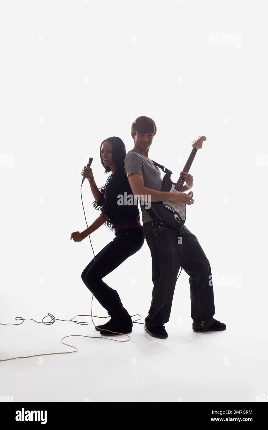 Une chanteuse et un homme jouant de la guitare électrique, studio shot, fond blanc, éclairage arrière Banque D'Images
