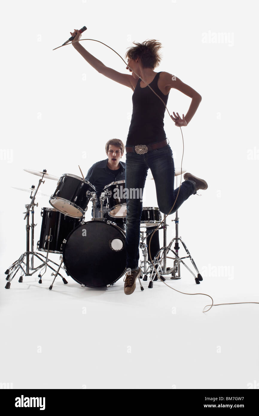 Une chanteuse d'un saut et qu'un homme sur la batterie de la scène, Studio shot, fond blanc, éclairage arrière Banque D'Images