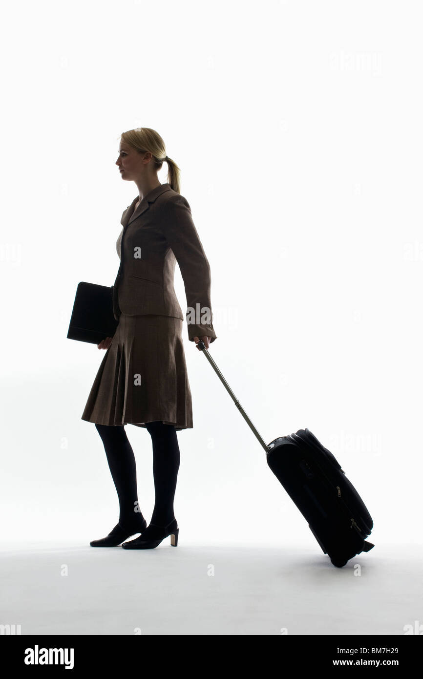 Une businesswoman pulling a transporter sur roues et la tenue d'un portefeuille Banque D'Images