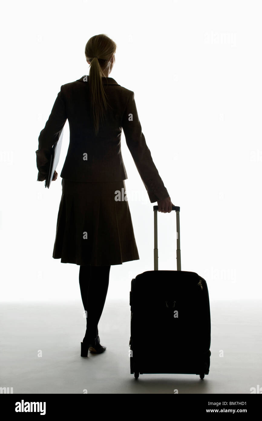 Une businesswoman pulling a transporter sur roues et la tenue d'un portefeuille Banque D'Images