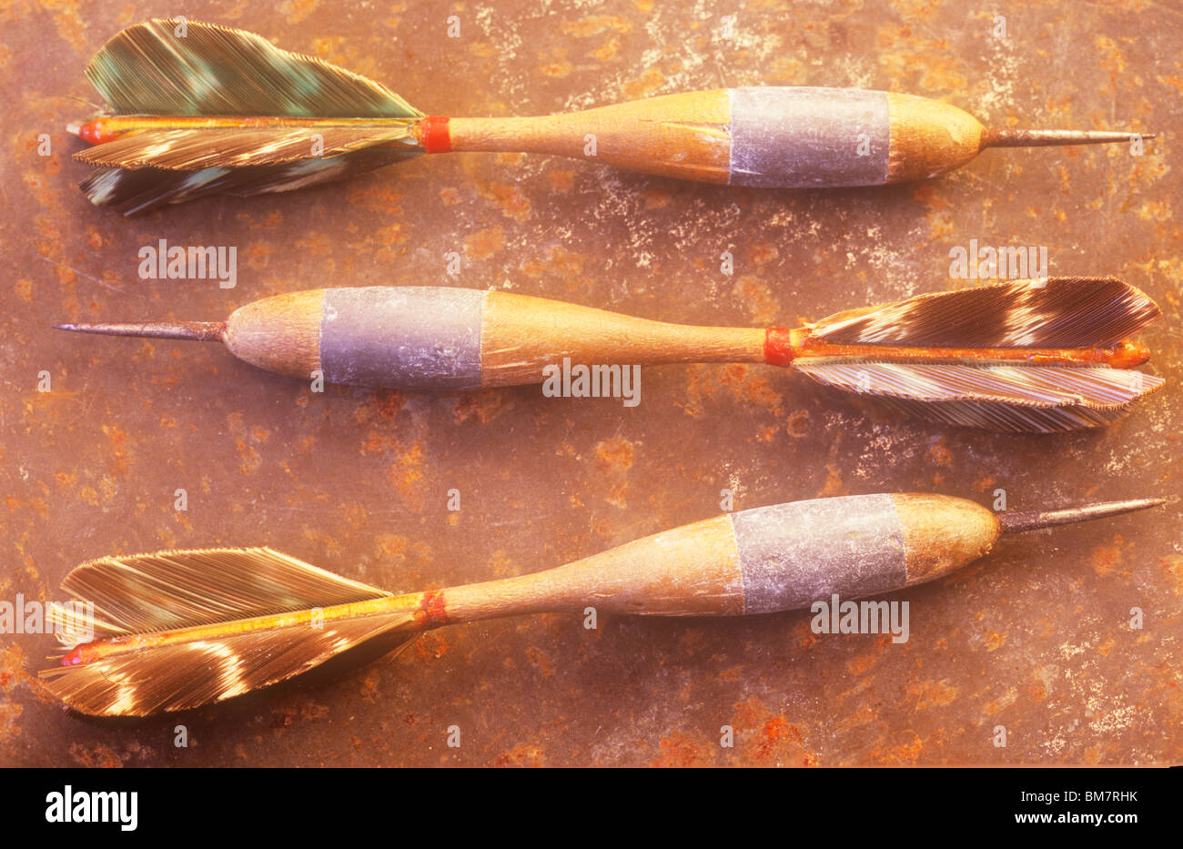 Ensemble de 3 anciennes de fléchettes fléchettes faits de bois et de plumes  de plomb métal couché sur feuille de métal rouillé en lumière chaude Photo  Stock - Alamy