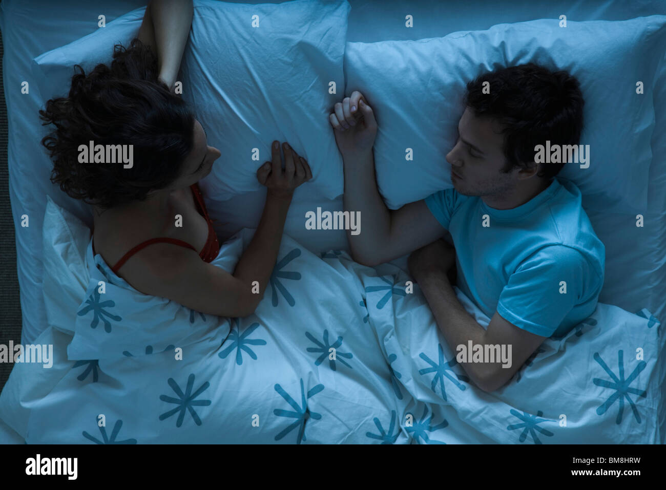 Couple lying together in bed, woman watching man sleeping Banque D'Images