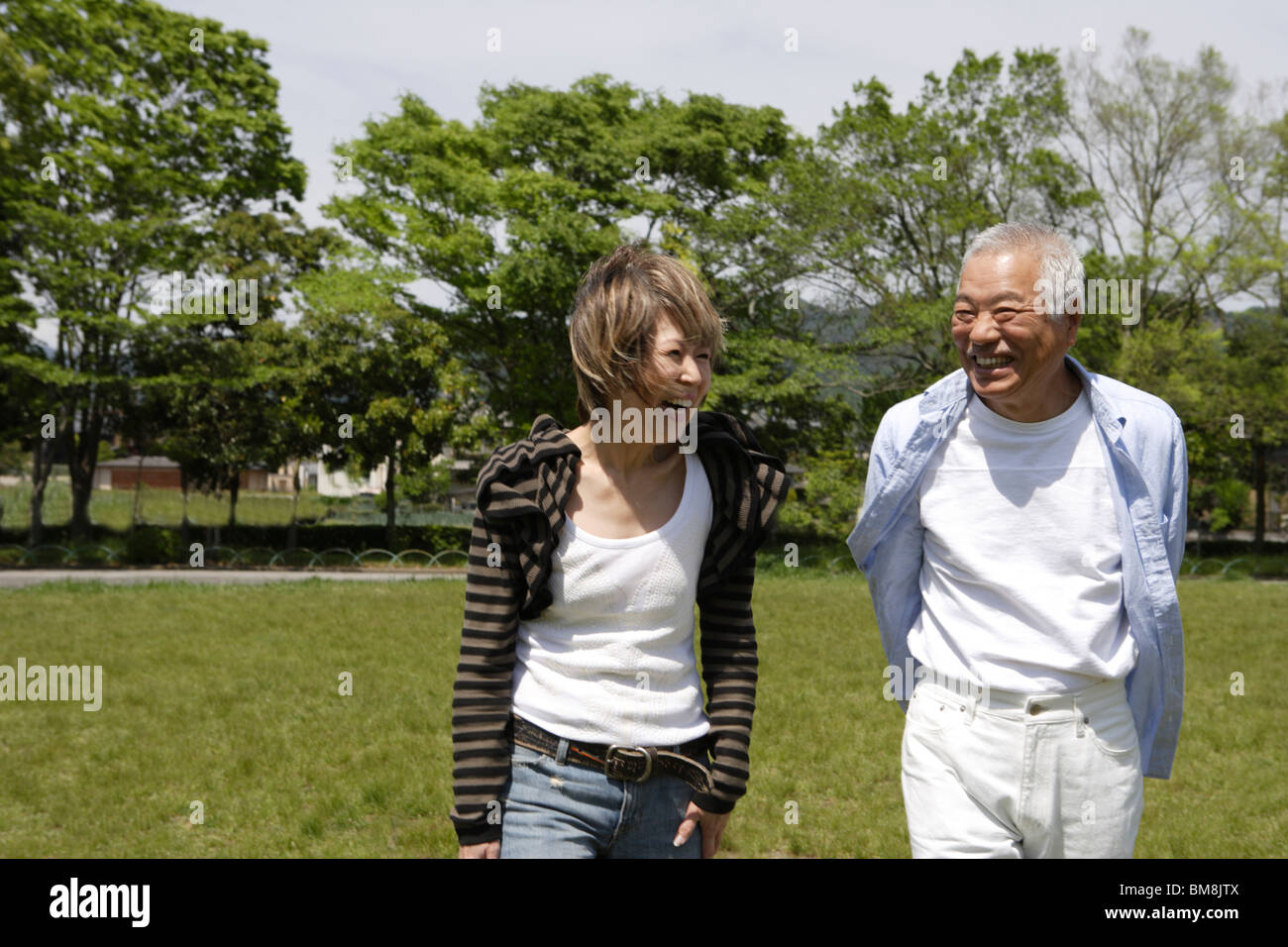 Man woman walking in park, smiling Banque D'Images