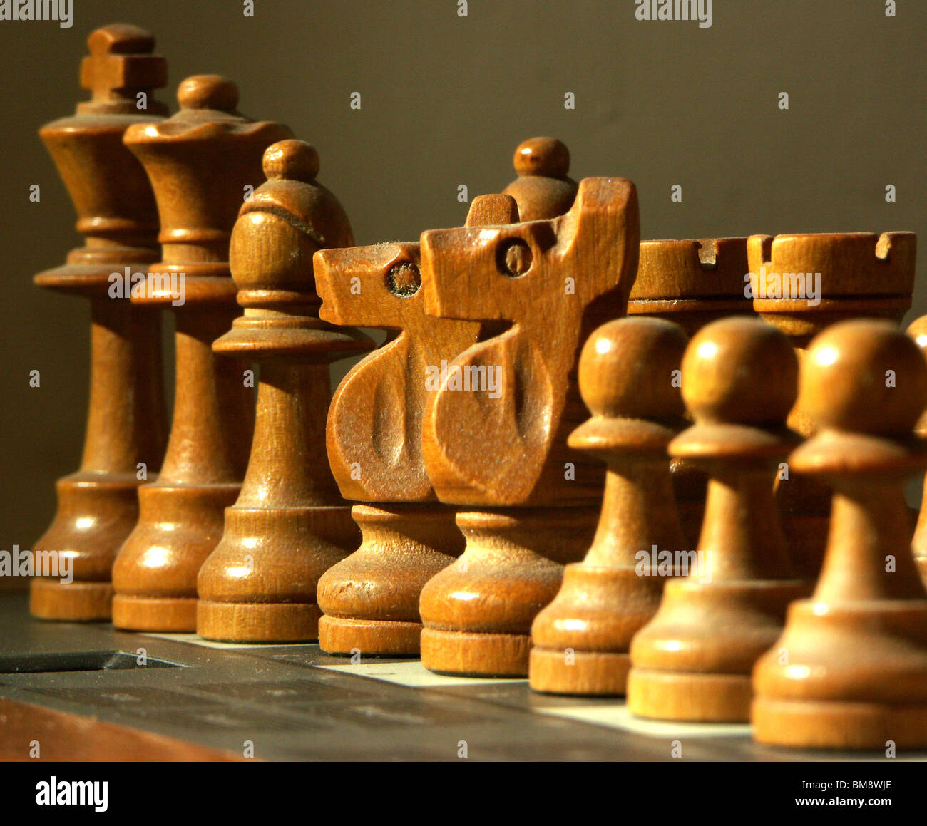 Close-up des pièces d'échecs dusty éclairé par la lumière aligné dans l'ordre de hauteur sur systèmes électroniques Banque D'Images