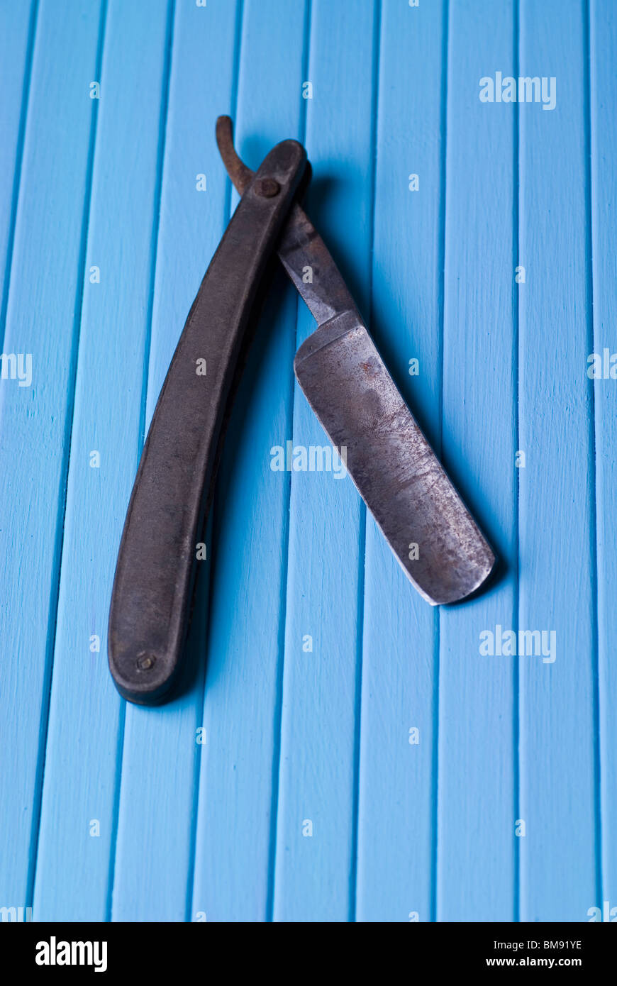 Vieille fardée rouillé barbier rasage rasoir sur un fond de bois bleu Banque D'Images