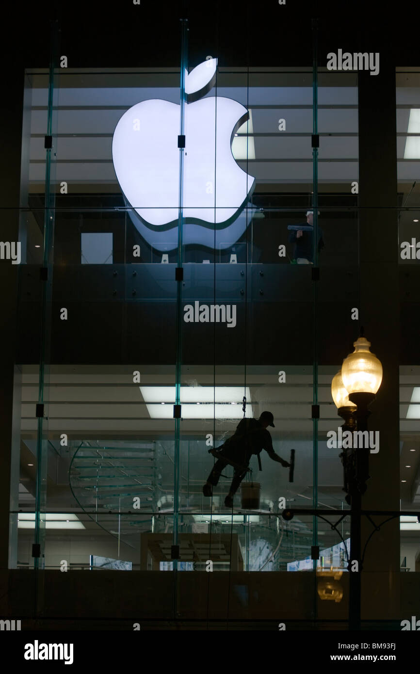 Window Washer suspendus par des cordes et le nettoyage de mur rideau en verre sur la face avant d'un Apple Store. Banque D'Images