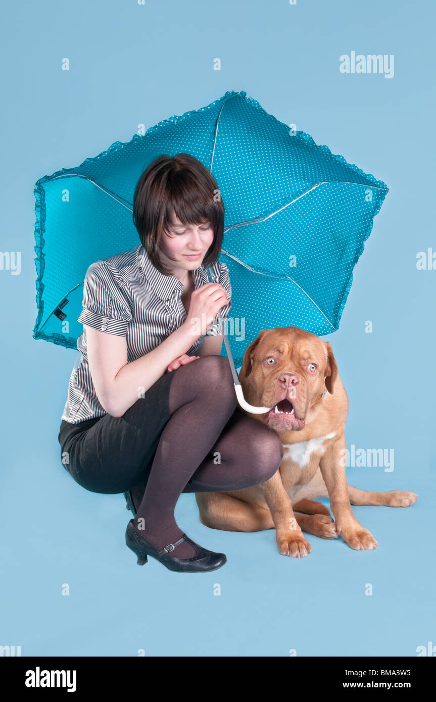 Fille avec un parapluie et un chien couché à ses pieds Banque D'Images