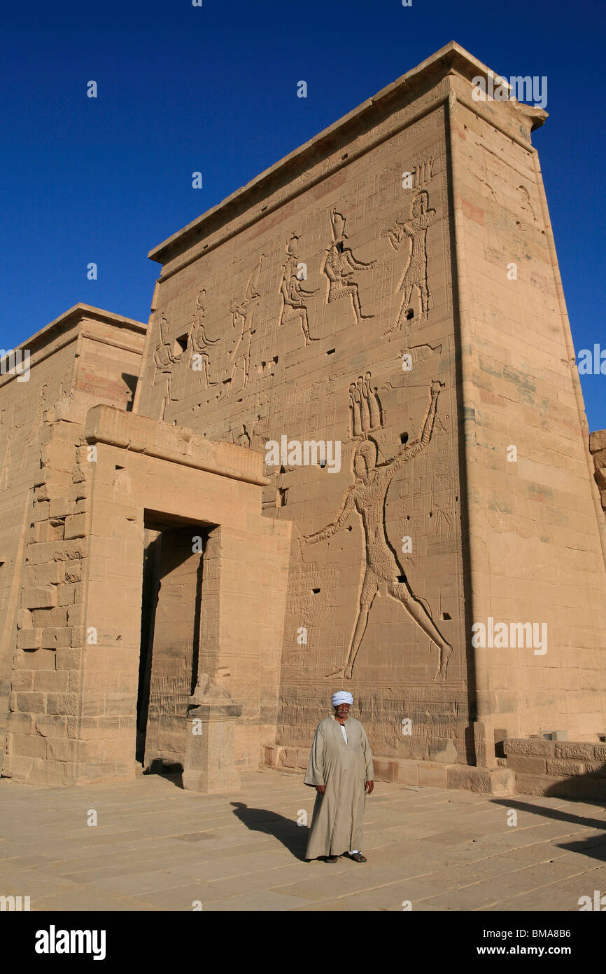 L'Homme égyptien en costumes traditionnels en dehors du Premier pylône du Temple d'Isis à Philae, bon maintenant sur l'Île Agilka en Egypte Banque D'Images