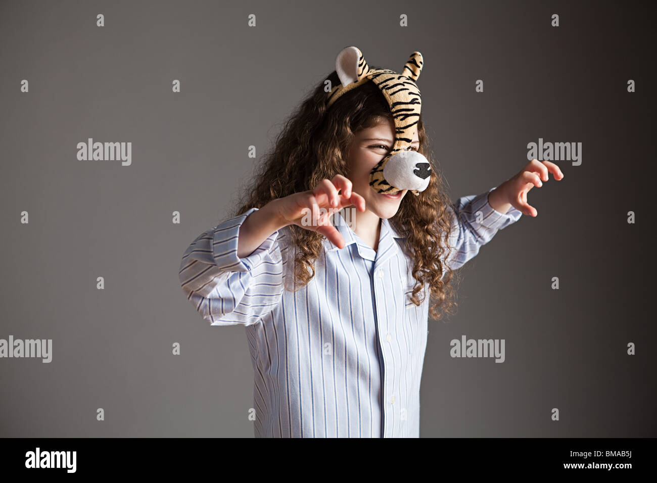 Jeune fille portant un masque de tigre rugissant, Banque D'Images