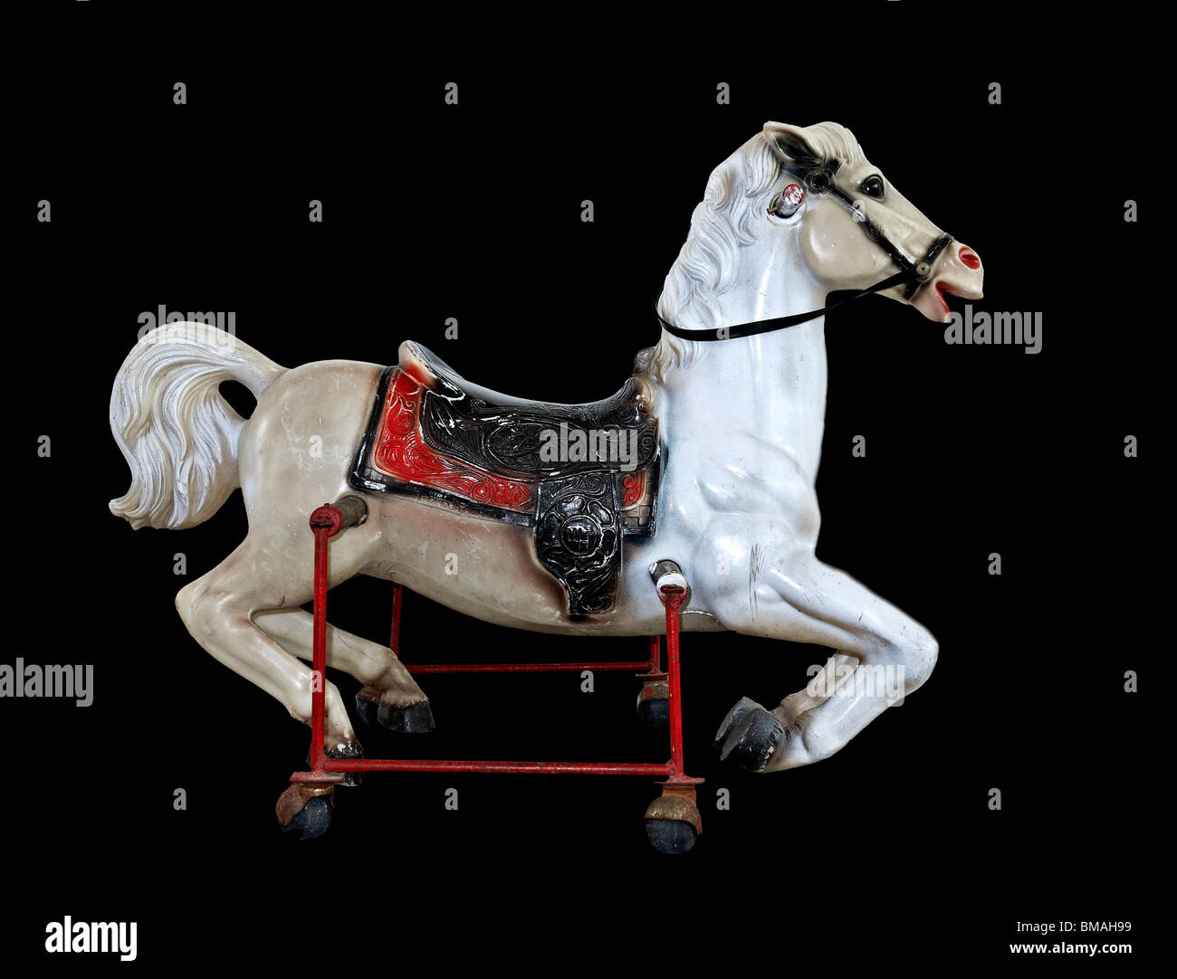 Cheval à bascule. Vieux cheval à bascule antique en métal sur des roues contre un sol noir Banque D'Images