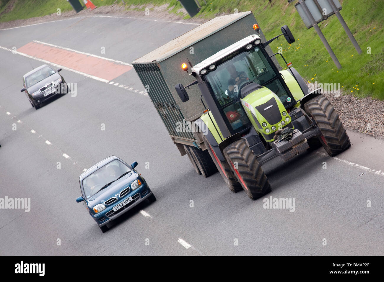Trafic routier véhicule agricole tracteur lent sur l'A75 avec petite voiture devant elle UK Banque D'Images