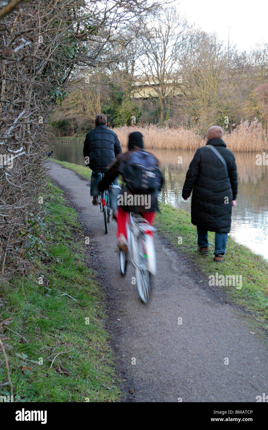 Les cyclistes passant un piéton sur un chemin à côté du Grand Union Canal à Brentford, Middx. Bicyclettes (floue) Banque D'Images