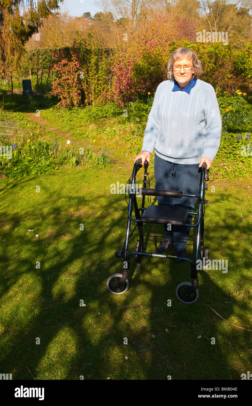 Un modèle photo parution d'une femme âgée avec son déambulateur rollator ( ) dans un chalet jardin dans Suffolk , Angleterre , Royaume-Uni Banque D'Images