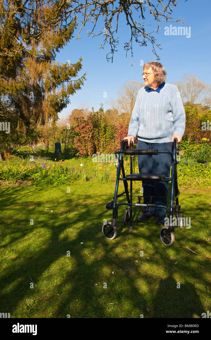 Un modèle photo parution d'une femme âgée avec son déambulateur rollator ( ) dans un chalet jardin dans Suffolk , Angleterre , Royaume-Uni Banque D'Images
