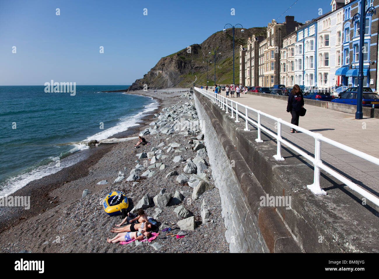 Les gens en train de bronzer sur une plage et promenade à pied sur le front de mer de Galles Aberystwyth UK Banque D'Images