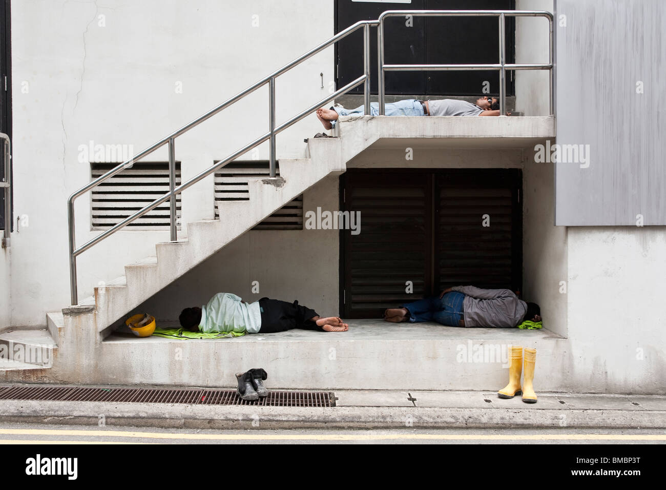 Les travailleurs migrants de prendre une sieste au cours de sa pause déjeuner dans le quartier central des affaires à Singapour Banque D'Images