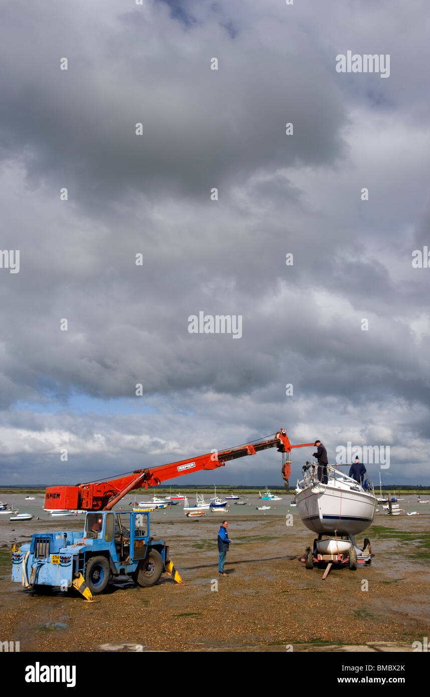 Entretien de bateaux sur la plage à marée basse sur l'île britannique Essex Mersea Banque D'Images