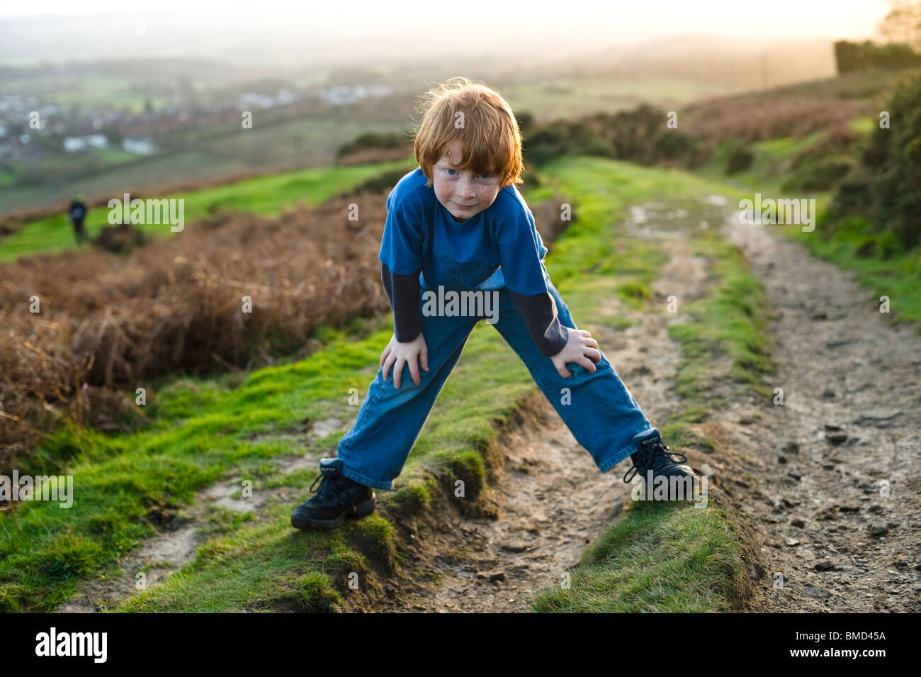 Jeune garçon rire et jouer en marchant au coucher du soleil dans la campagne. Banque D'Images