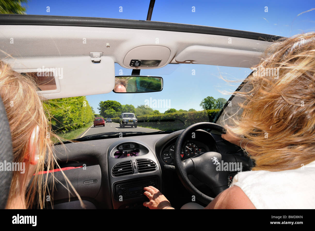 Open top voiture avec conducteur et passager féminin sur route ouverte Banque D'Images