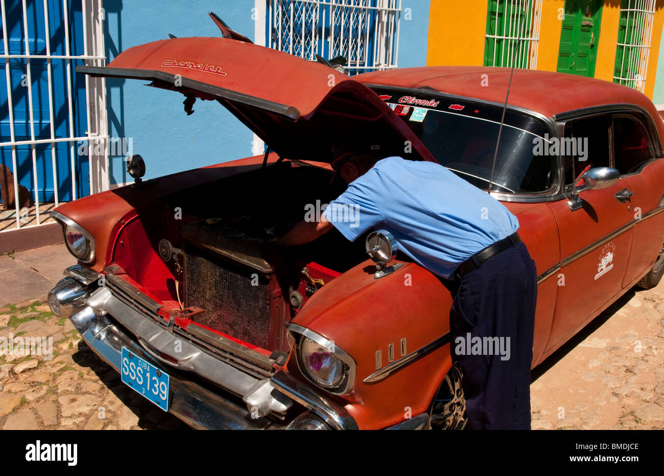 Homme réparait sa vieille Chevy classique sur rue pavée de Trinidad Cuba Banque D'Images