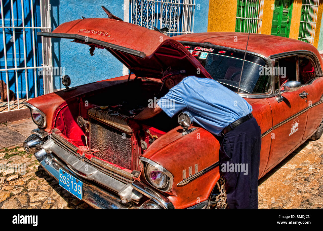Homme réparait sa vieille Chevy classique sur rue pavée de Trinidad Cuba Banque D'Images