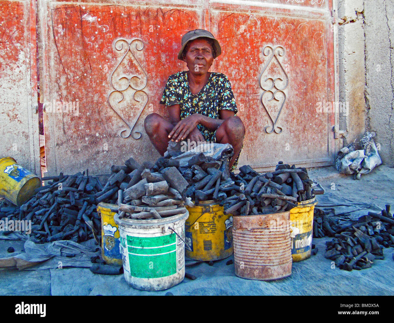 Une femme vend du charbon dans une rue de Gonaïves, Haïti, où le déboisement pour le carburant est endémique Banque D'Images