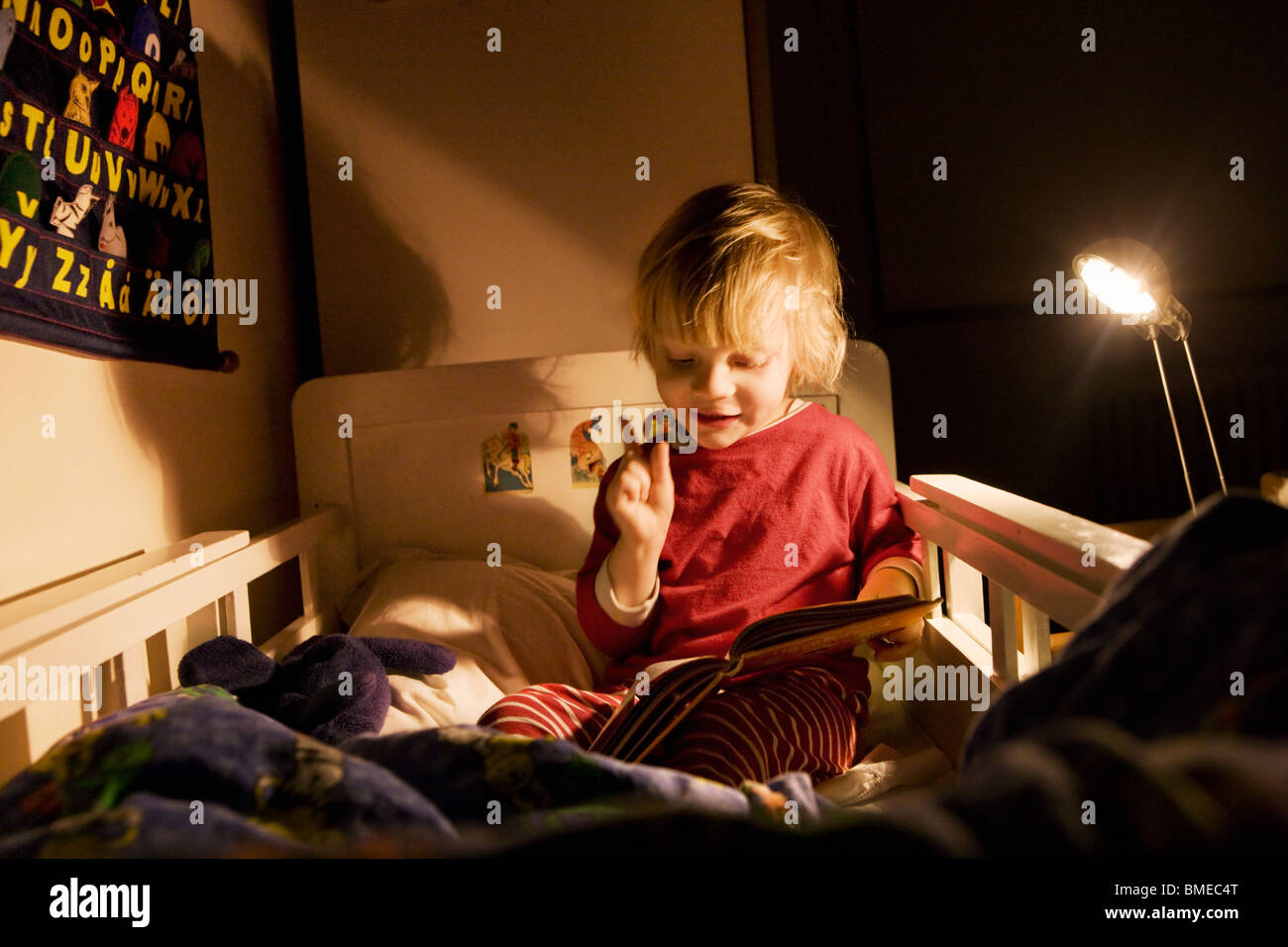 Boy reading book on lit la nuit Banque D'Images