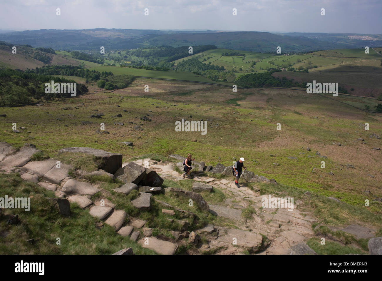 Les marcheurs près de haut de Stanage Edge falaises de pierre meulière, parc national de Peak District, Derbyshire. Banque D'Images