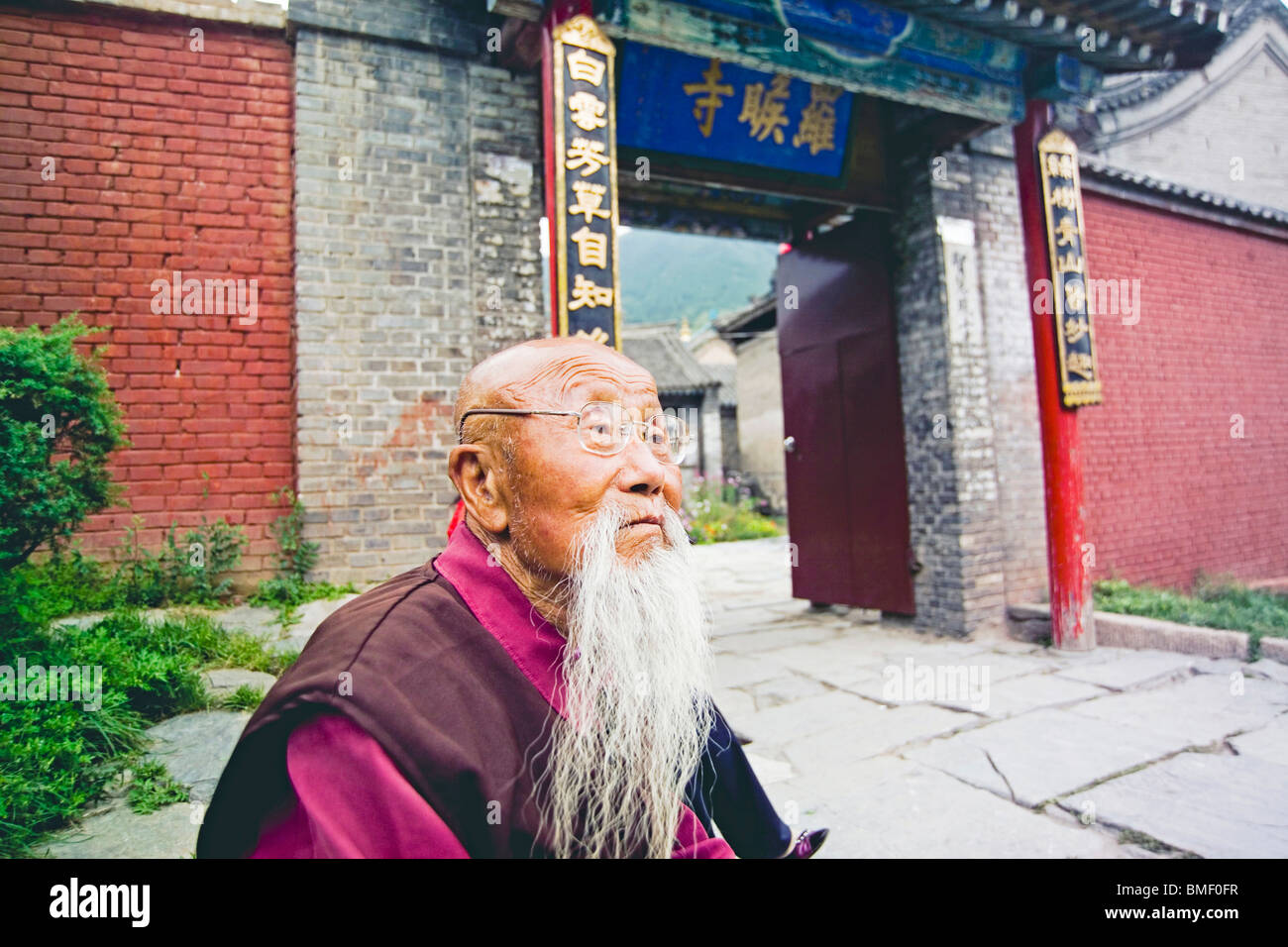Vieux moine assis à côté de la porte du temple, Le Mont Wutai Luohou, Xinzhou City, province de Shanxi, Chine Banque D'Images