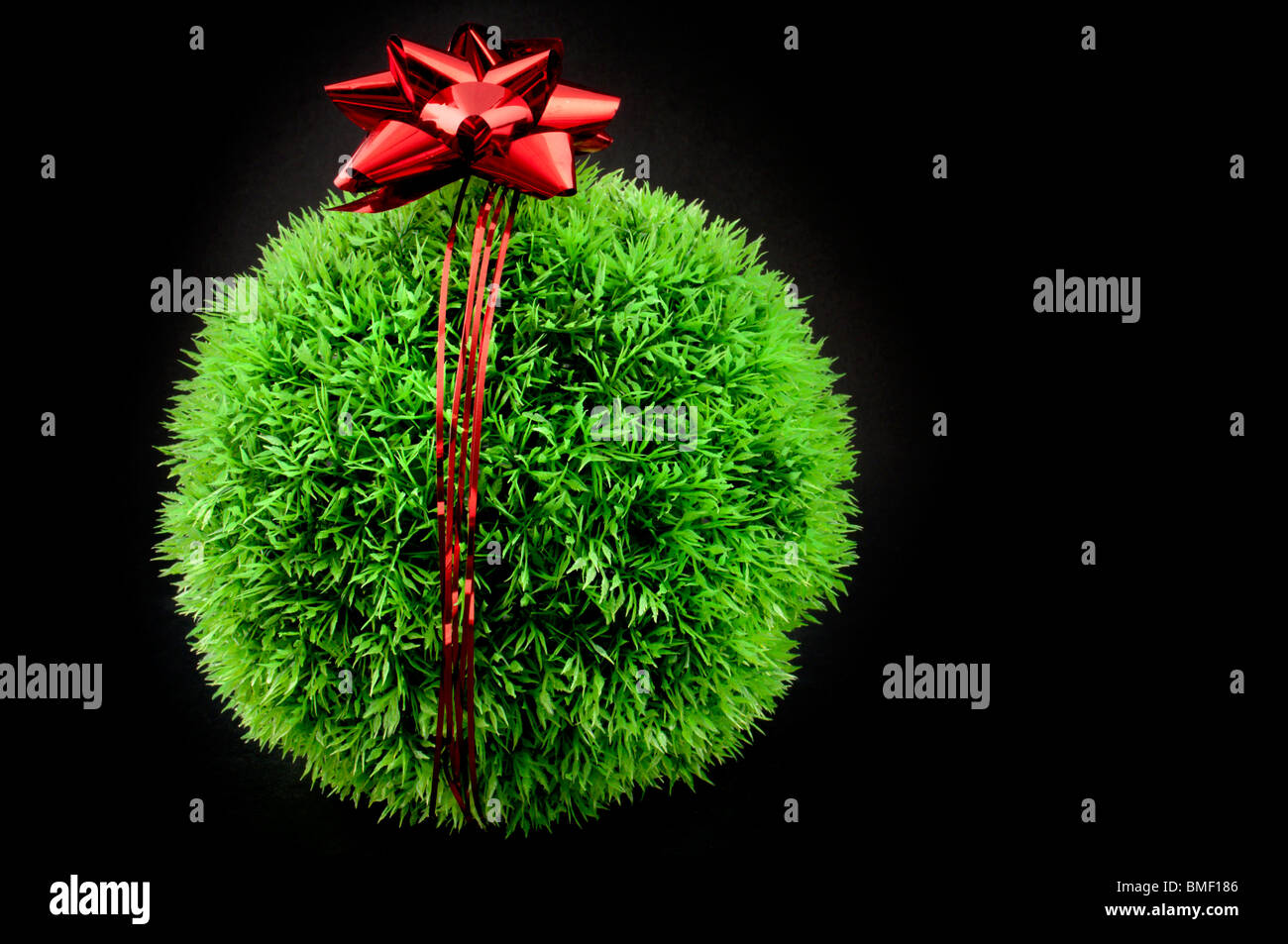 L'herbe verte balle avec arc rouge et ruban au-dessus de lui, un cadeau pour la terre Banque D'Images