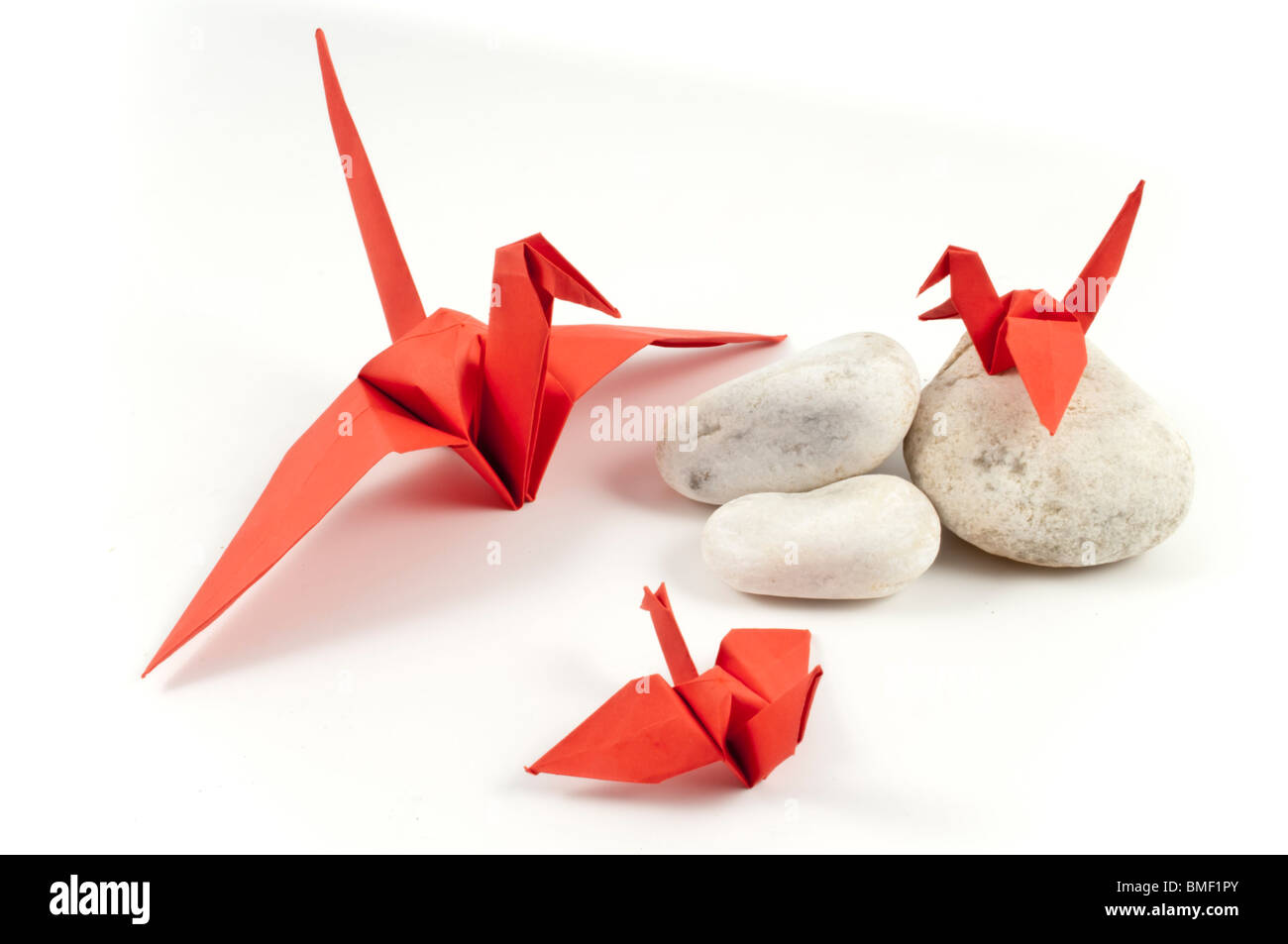 Grue Origami rouge et ses enfants sur les pierres blanches Banque D'Images