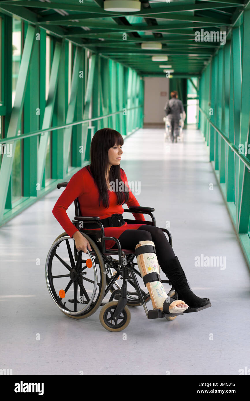 Jeune femme avec une jambe dans le plâtre et à l'hôpital en fauteuil roulant Banque D'Images