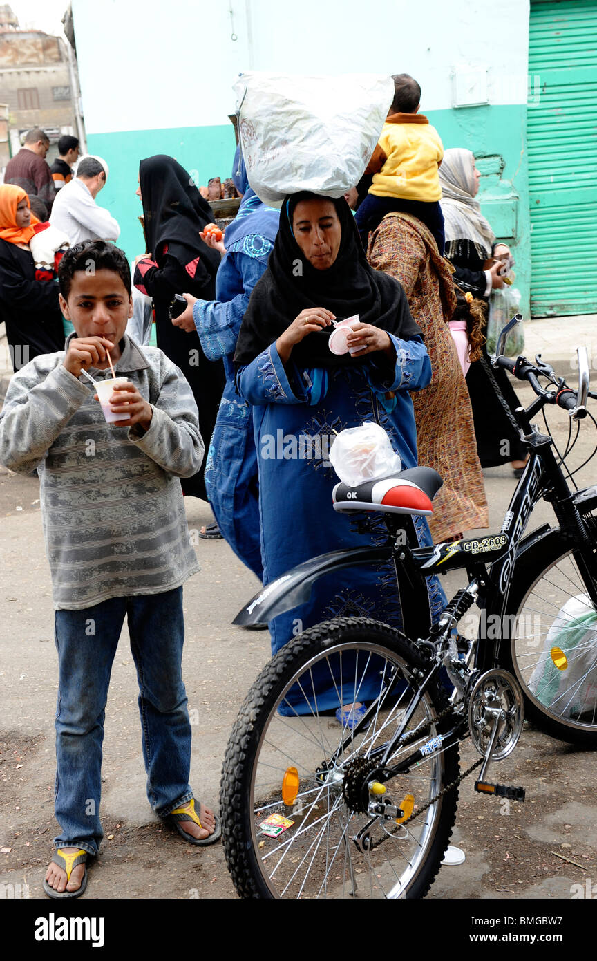 Jeune garçon de boire du jus de canne à sucre,souk goma (marché du vendredi), la rue du marché, le sud de cimetières, district de Khalifa ,Le Caire Banque D'Images