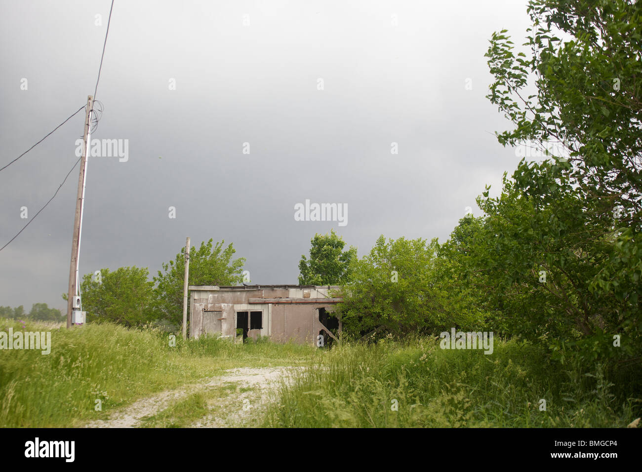 Une remise se trouve à la fin d'une route de gravier comme une tempête dans la région. Banque D'Images